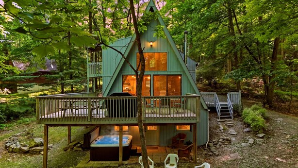 A cabin with a deck, hot tub, and outdoor seating. - Lost Pines- Hot Tub | Pet Friendly | Family Friendly (Berkeley Springs)