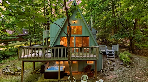 A cabin with a deck, hot tub, and outdoor seating.
