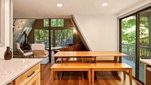 A modern kitchen with wooden countertops, a dining area with benches, and a large sliding glass door leading to an outdoor deck. - Lost Pines- Hot Tub | Pet Friendly | Family Friendly (Berkeley Springs)
