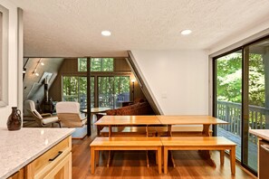 A modern kitchen with wooden countertops, a dining area with benches, and a large sliding glass door leading to an outdoor deck.