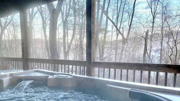 A hot tub with a wooden deck and a view of leafless trees. - Wildflower- Themed | Pet Friendly | Private Hottub (Berkeley Springs)