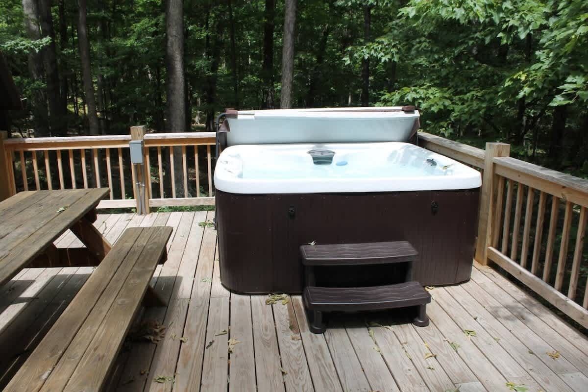 A hot tub on a wooden deck surrounded by trees.