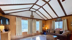 A cabin interior with a wooden interior, a sofa, a television, and a fireplace. - "Evergreen" Private, creek-side escape (Berkeley Springs)