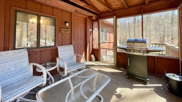 A covered outdoor area with wooden benches, a grill, and a view of the forest. - "Evergreen" Private, creek-side escape (Berkeley Springs)