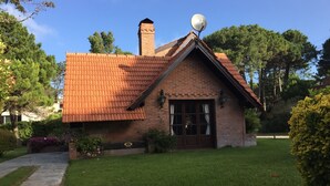 A brick house with a tiled roof, a chimney, and a satellite dish.