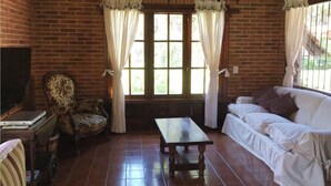 A cozy living room with a brick wall, a sofa, a chair, a small table, and a TV.