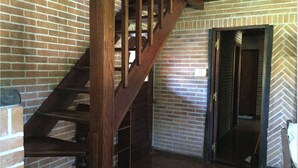 A brick interior with a wooden staircase leading to a door.