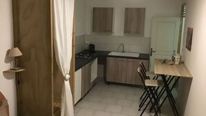 Eine kleine Küche mit Herd, Spüle und Holzschränken.