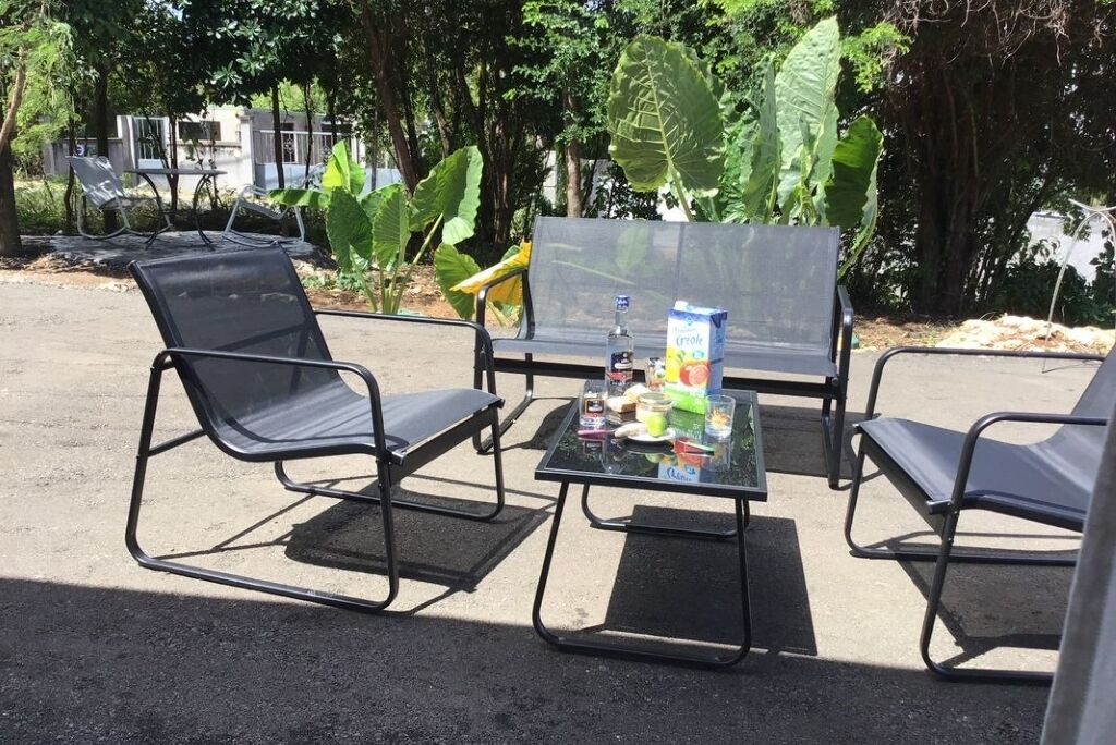 A table with chairs and a bottle of water, surrounded by greenery.