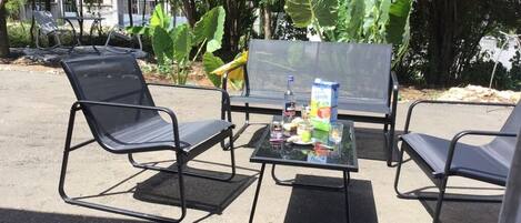 Une table avec des chaises et une bouteille d’eau, entourée de verdure.