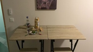 Ein Esstisch mit einem Zebra-Gemälde darüber, eine Flasche, ein Glas und einige Speisen auf dem Tisch.