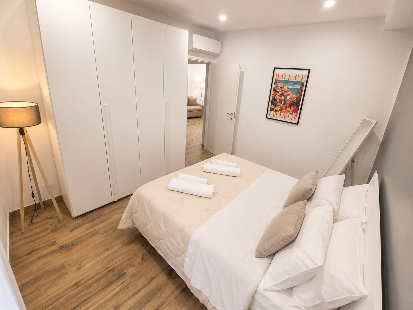 A bedroom with a bed, white curtains, a poster, and a lamp.