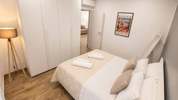 A bedroom with a bed, white curtains, a poster, and a lamp.