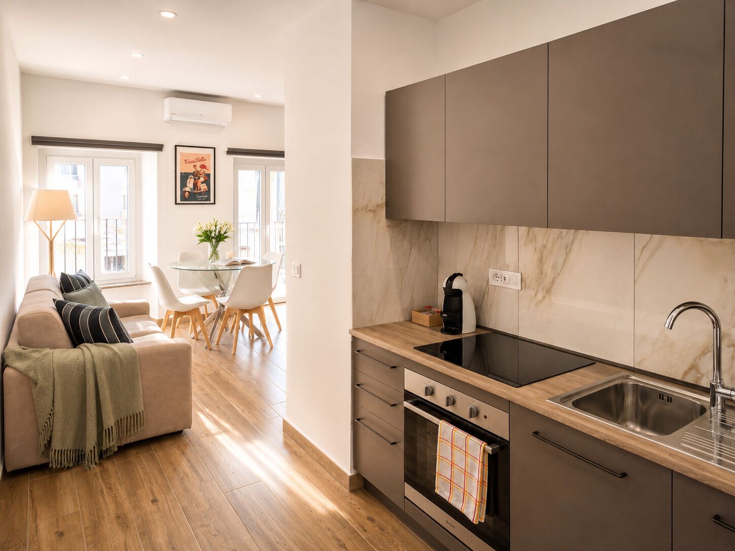 Una cucina moderna con forno a incasso, lavello e zona pranzo con tavolo e sedie.