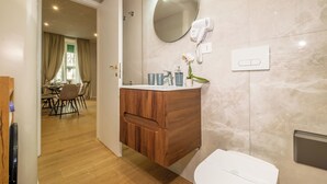 Un baño moderno con tocador de madera, un espejo grande, un secador de pelo y un inodoro.