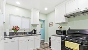 A kitchen with white cabinets, a black stove, and a microwave.