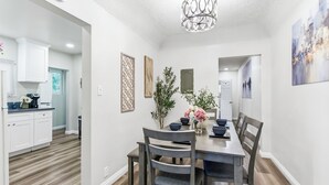 A dining area with a wooden table and chairs, a chandelier, and decorative wall art.
