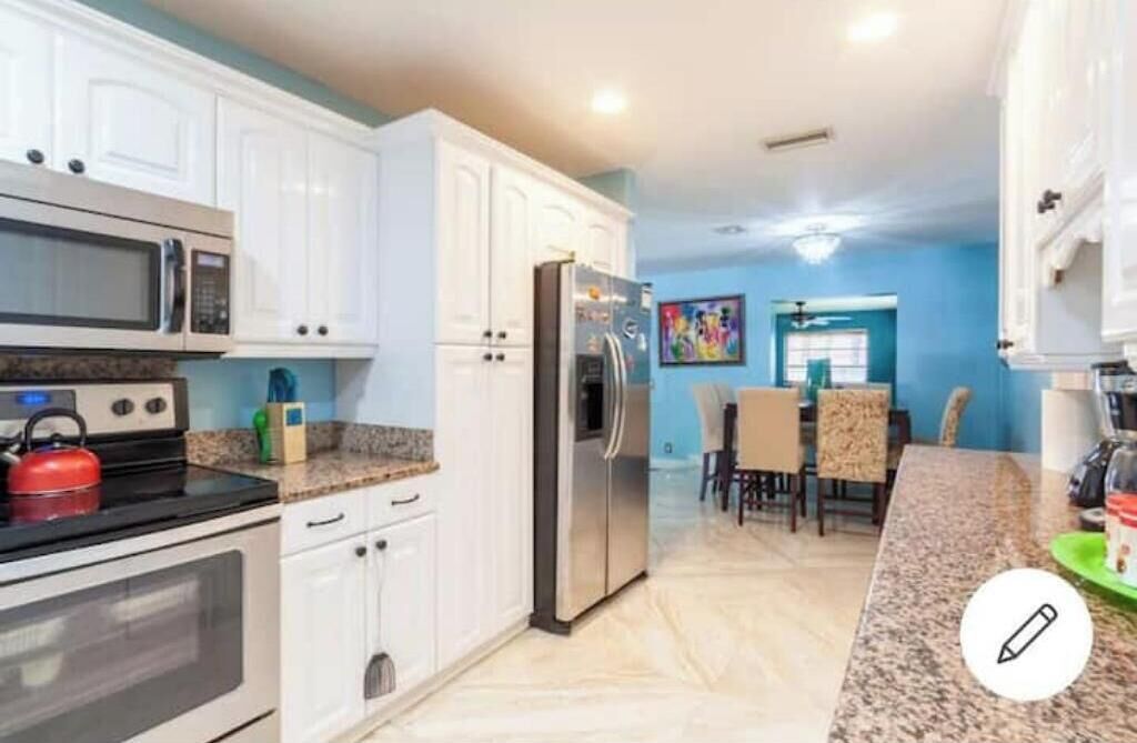 A modern kitchen with white cabinets, stainless steel appliances, and a granite countertop.