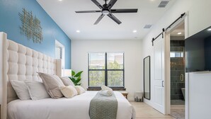 A modern bedroom with a large bed, a ceiling fan, and a view of the outside through the window. - Beautiful Elegant New Tampa Luxury Home (Tampa)