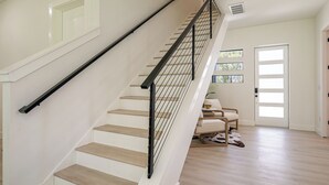 A staircase with a black handrail and wooden steps, leading to a room with a door and a window. - Beautiful Elegant New Tampa Luxury Home (Tampa)