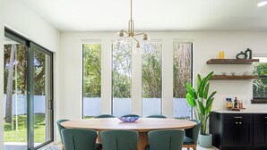 A modern dining area with a round table, green chairs, and a hanging light fixture. - Beautiful Elegant New Tampa Luxury Home (Tampa)