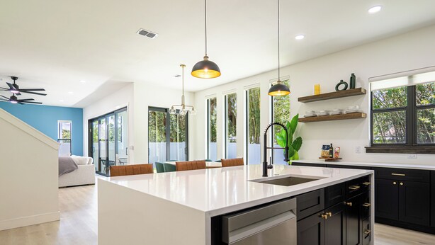 A modern kitchen with a central island, black cabinets, and a built-in dishwasher. - Beautiful Elegant New Tampa Luxury Home (Tampa)