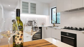 Una cocina moderna con armarios blancos, una estufa a gas y una ventana con vista a un jardín.