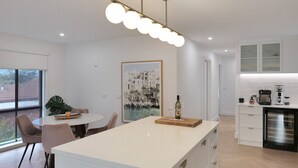 Una cocina moderna con una isla central, armarios blancos y una cafetera.
