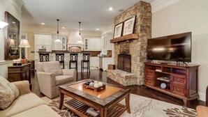 Una sala de estar con chimenea de piedra, televisor y comedor con sillas y mesa.
