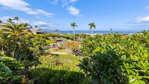A tropical resort with lush greenery, palm trees, and a view of the ocean.