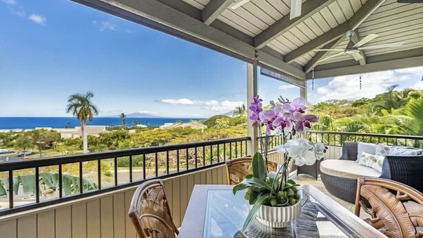 A balcony with a table, chairs, and a potted orchid.