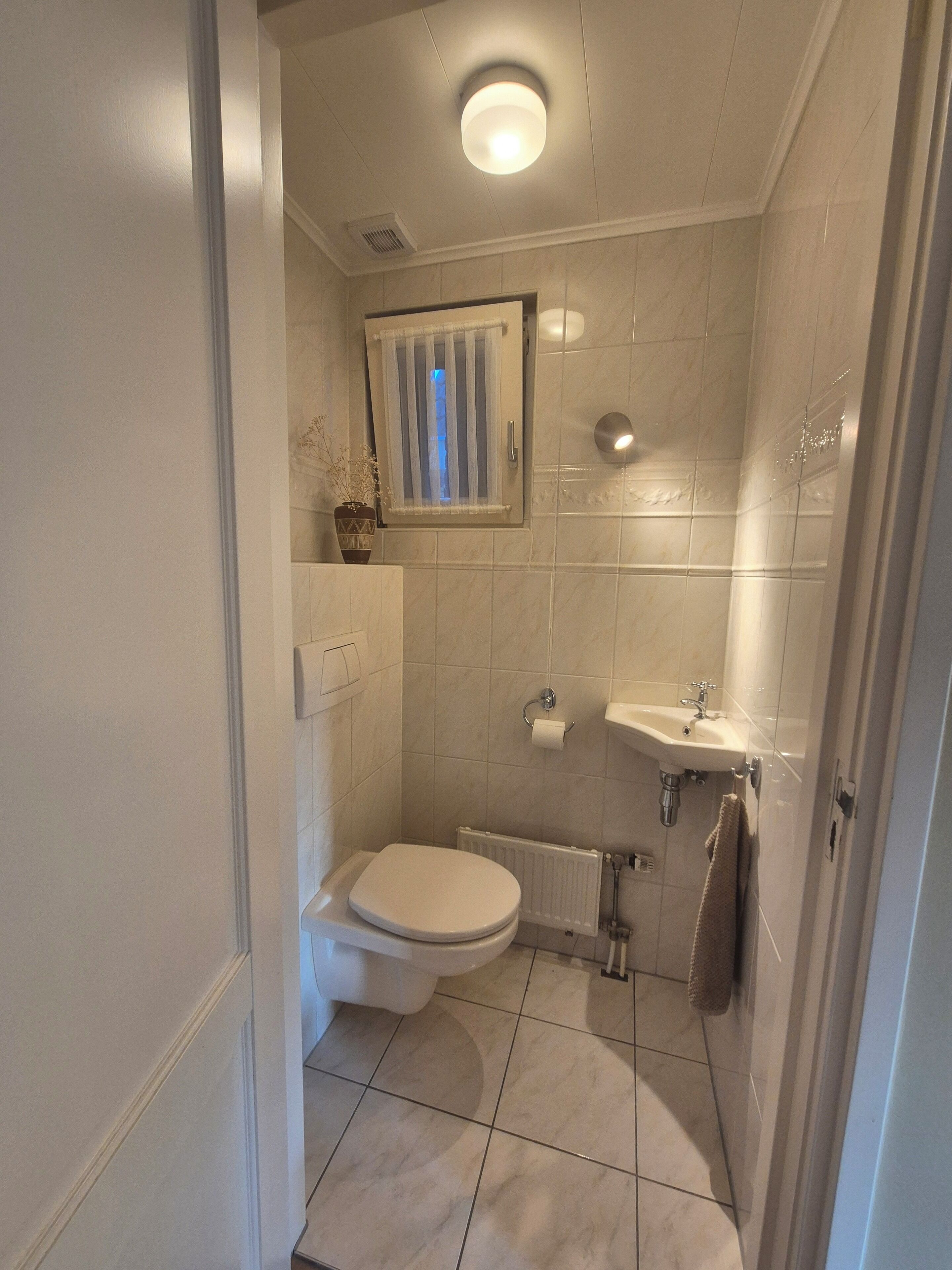 Un baño pequeño con inodoro, lavamanos y ducha.