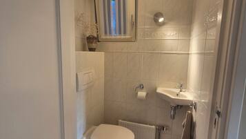 Un baño pequeño con inodoro, lavamanos y ducha.