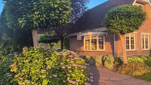 Ein Ziegelhaus mit gepflasterter Auffahrt und einem gepflegten Garten mit blühenden Pflanzen.