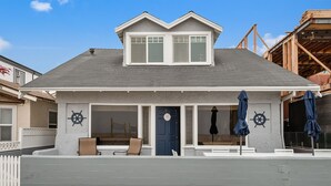 A two-story house with a porch, a blue door, and two ship wheel decorations. - 5 bedroom Cottage on the Strand! (Hermosa Beach)