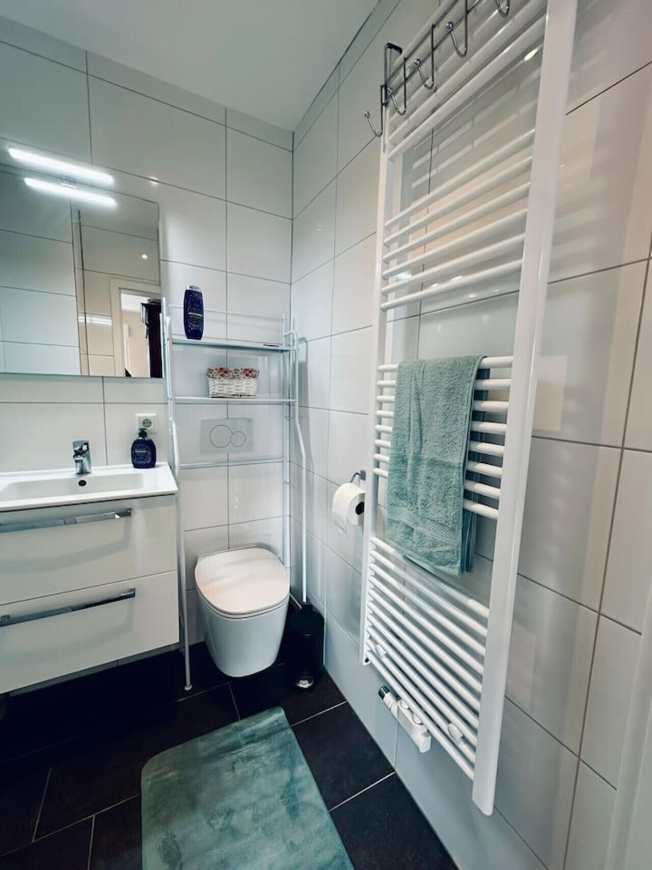 Ein modernes Badezimmer mit Waschbecken, Spiegel, Toilette und Handtuchhalter.