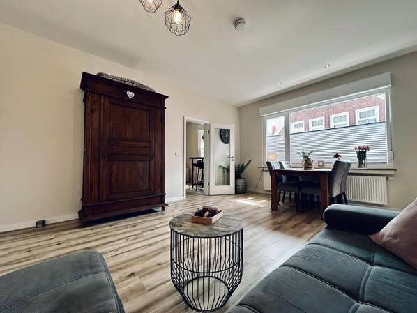 A spacious living room with a wooden cabinet, a round coffee table, and a dining area with a table and chairs.