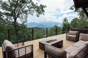 Eine Terrasse mit Gartenmöbeln, einer Feuerstelle und Blick auf Berge.