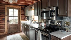 Een moderne keuken met roestvrijstalen apparatuur, houten keukenkastjes en een achterwand van steen.