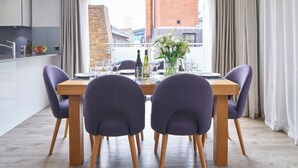 Un coin repas avec une table en bois, des chaises violettes et un vase de fleurs.