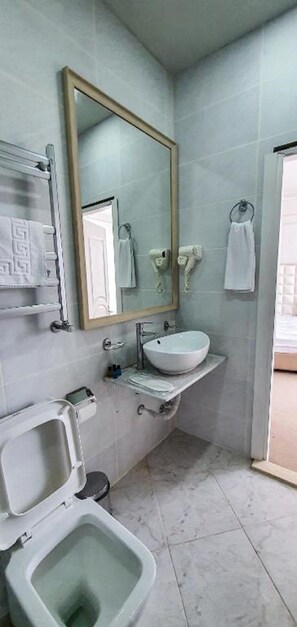 Une salle de bain avec un lavabo blanc, un miroir, des toilettes et un porte-serviettes.