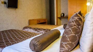 Une chambre d’hôtel avec deux lits, un téléviseur fixé au mur et une armoire en bois.