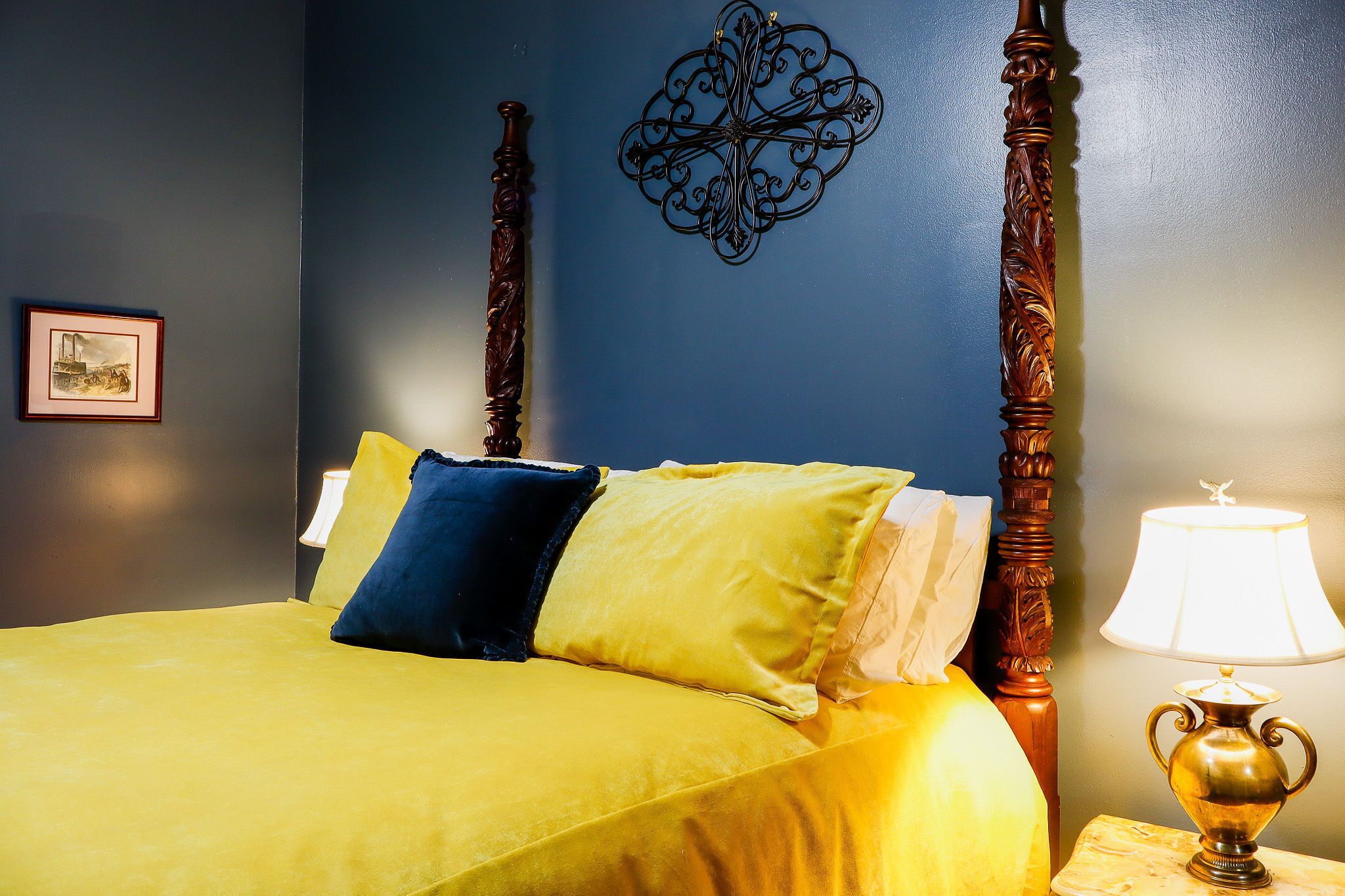 Un lit avec une tête de lit en bois, un élément décoratif mural et une lampe de chevet.