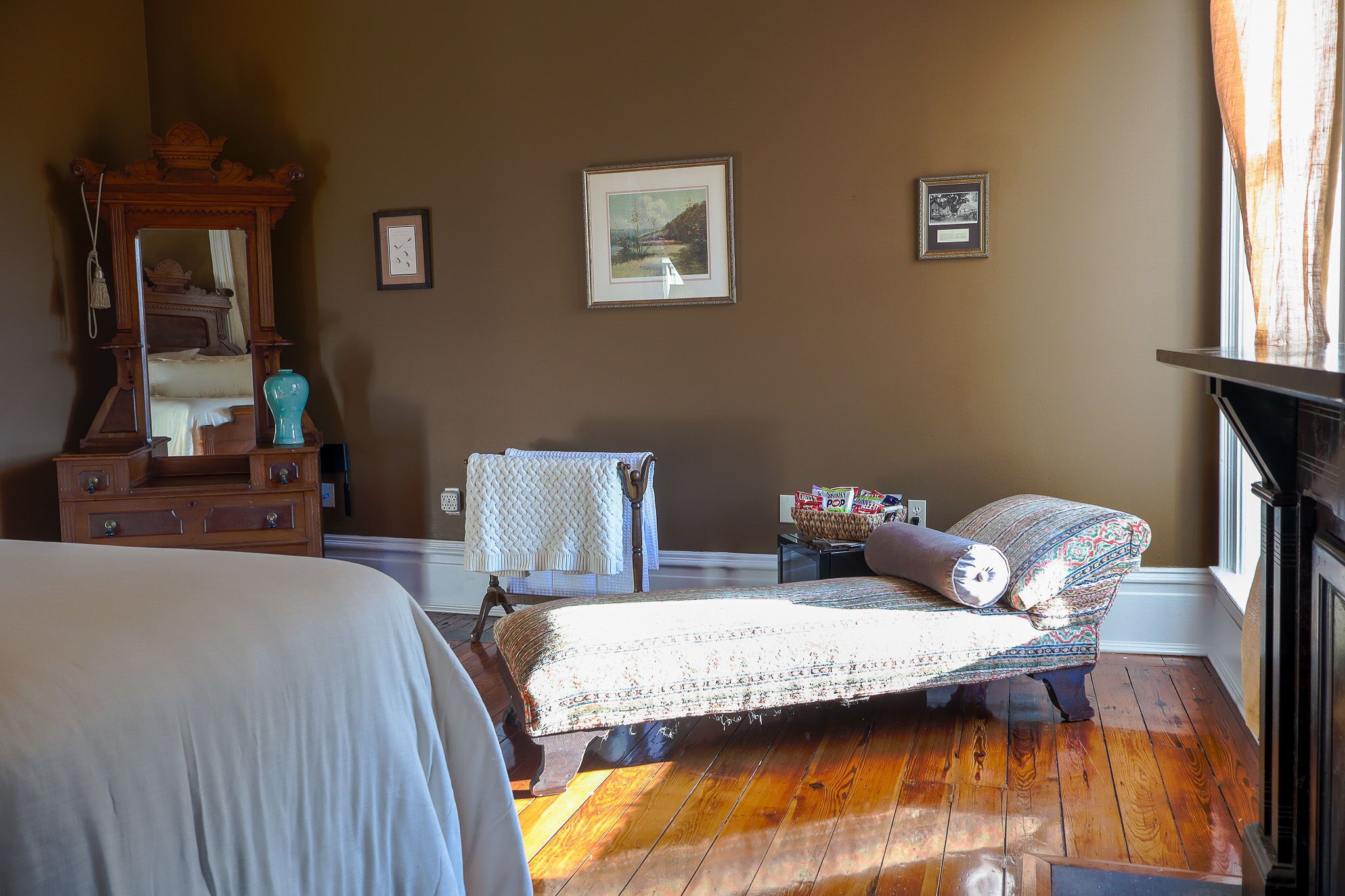 Un dormitorio con cama, cómoda, silla y ventana con cortinas.