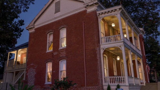 A two-story brick building with a balcony and large windows. - Baer House Inn (Vicksburg)