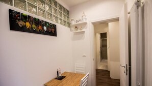 A small dining area with a wooden table and white chairs, a glass cabinet with decorative items, and a white door leading to another room. - GOLDEN SUITE (Venezia)