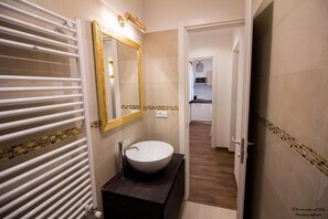A bathroom with a white sink, a large mirror, and a towel rack. - GOLDEN SUITE (Venezia)