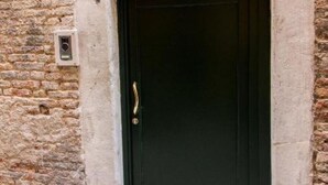 A black door with a brass handle, set in a stone wall with a security device mounted on the wall to the left. - GOLDEN SUITE (Venezia)
