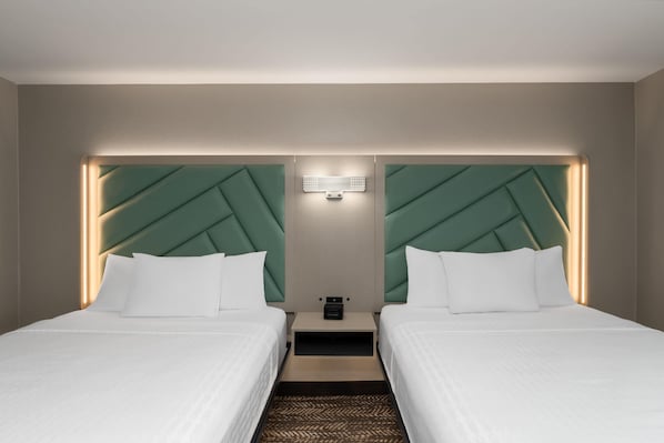 A hotel room with two beds, a nightstand, a wall-mounted light, and a geometric headboard design. - Wingate By Wyndham Jackson (Jackson)