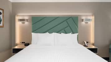 Une chambre d’hôtel avec un grand lit, deux tables de chevet, une tête de lit verte et des lampes fixées au mur.
